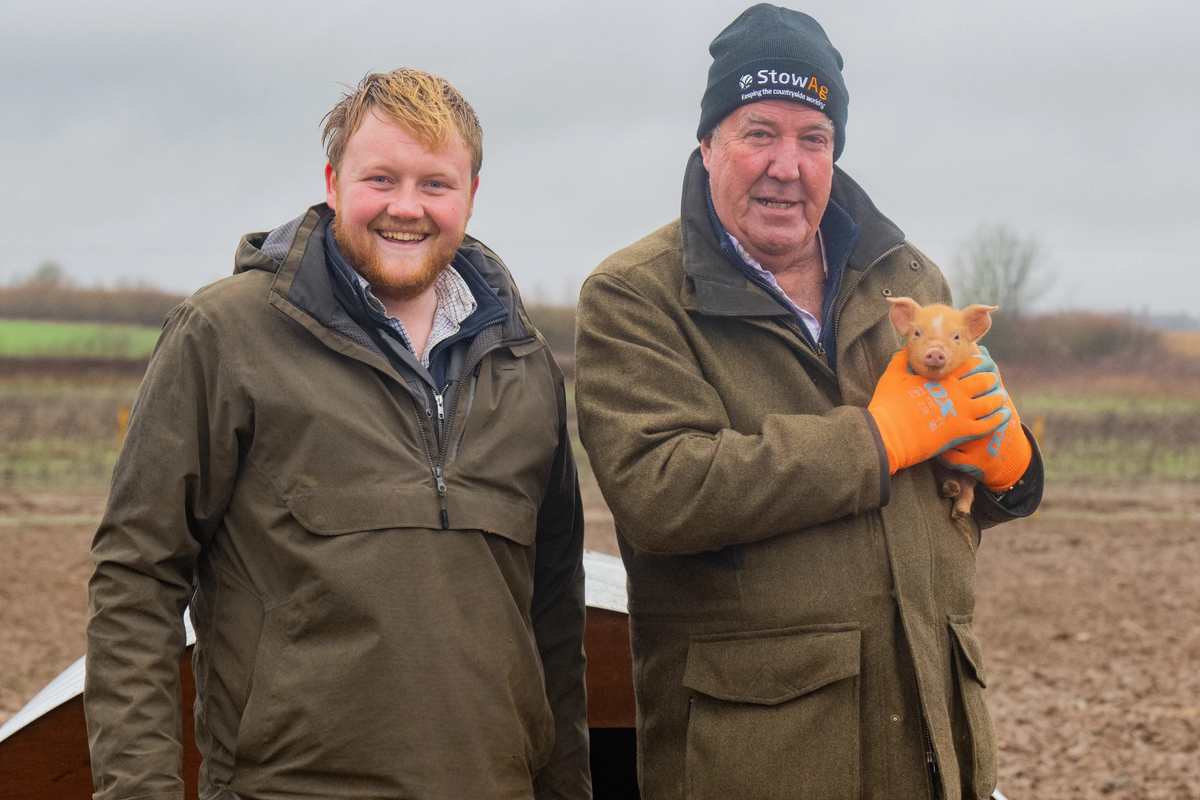 jeremy clarkson and kaleb cooper pictured with pigs in a field in a promotional picture for season 3 of clarksons farm series on prime video