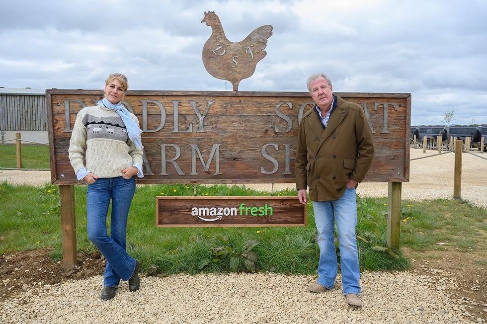 jeremy clarkson and lisa hogan pose in front of the diddly squat farm shop sign