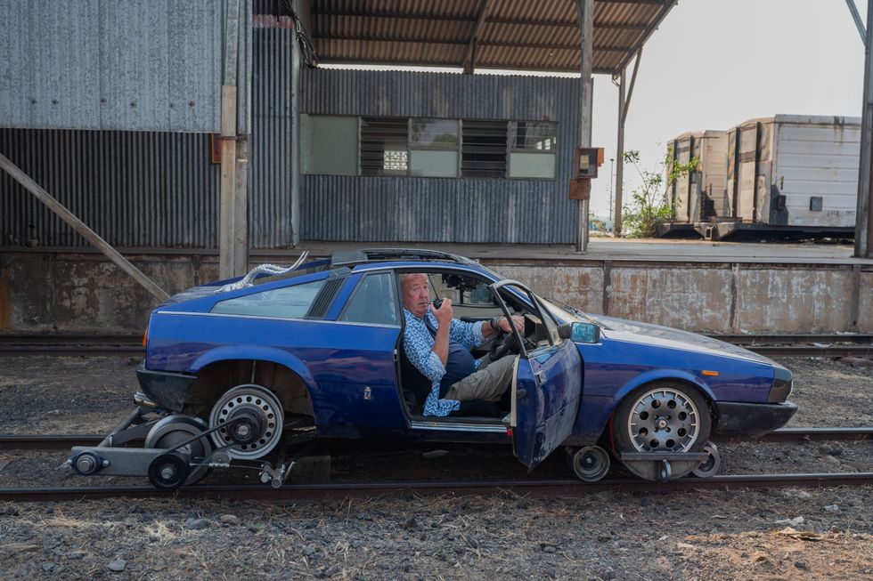 jeremy clarkson sits in a sports car on a railway track