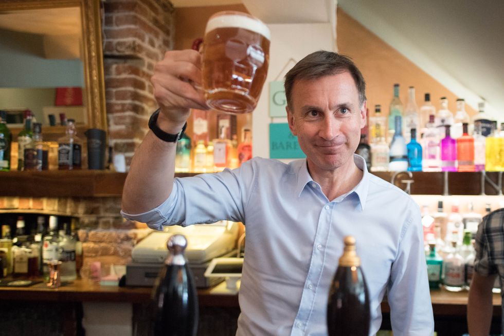 Jeremy Hunt raising a pint of beer in a pub.