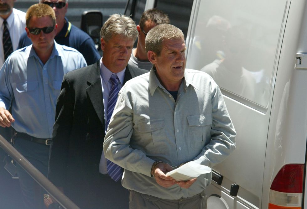 John Murdoch is escorted, in handcuffs, from the Adelaide Magistrates' Court after facing an extradition hearing November 13, 2003