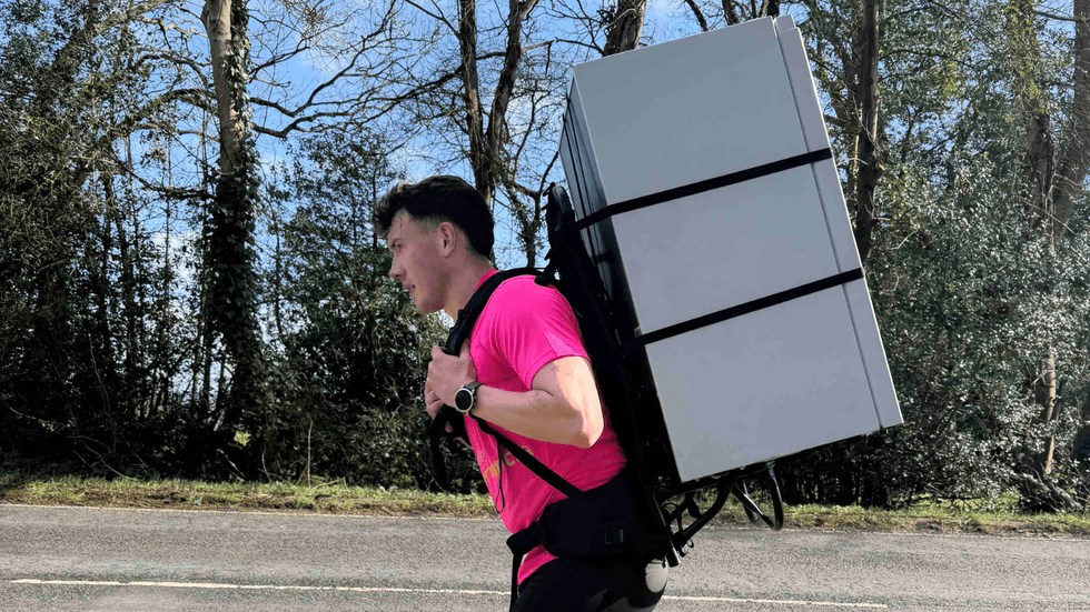 Jordan Adams running with fridge strapped to his back