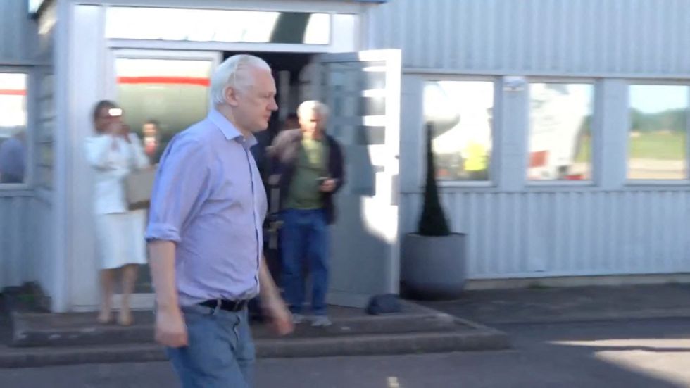 Julian Assange walks to board a plane in London