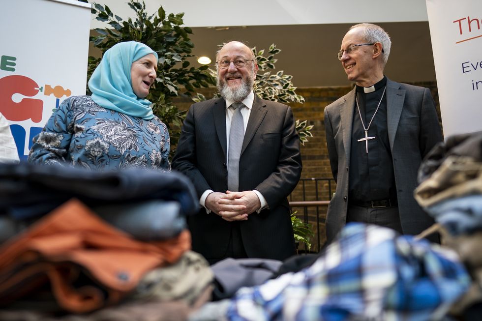 Julie Siddiqi, Chief Rabbi Ephraim Mirvis and the Archbishop of Canterbury Justin Welby help sort clothing as they join other faith leaders in taking part in the Big Help Out in April 2023
