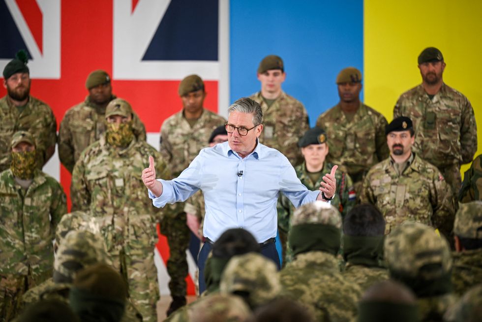 Keir Starmer (C) speaks on stage to the troops during a visit to a British army base in the west of England