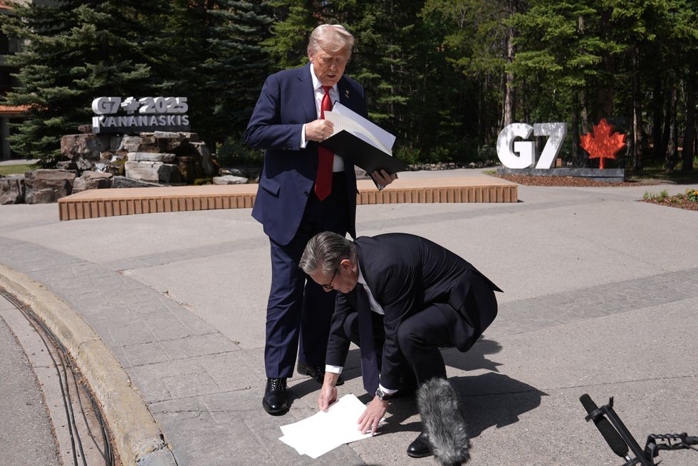 Keir Starmer picks up papers dropped by Donald Trump