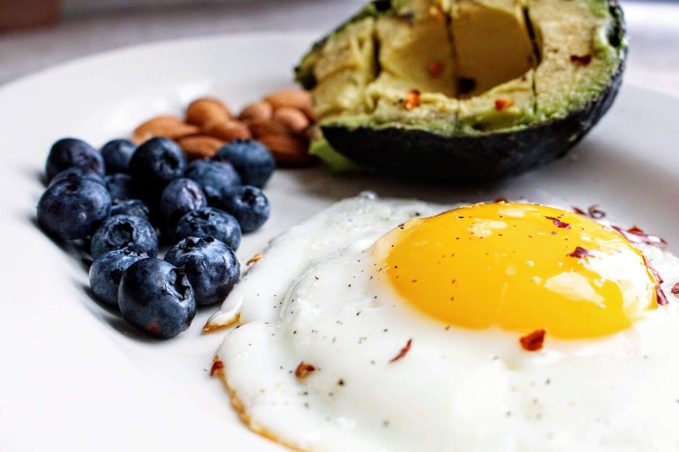 Keto foods on plate with egg, fruit, avocado