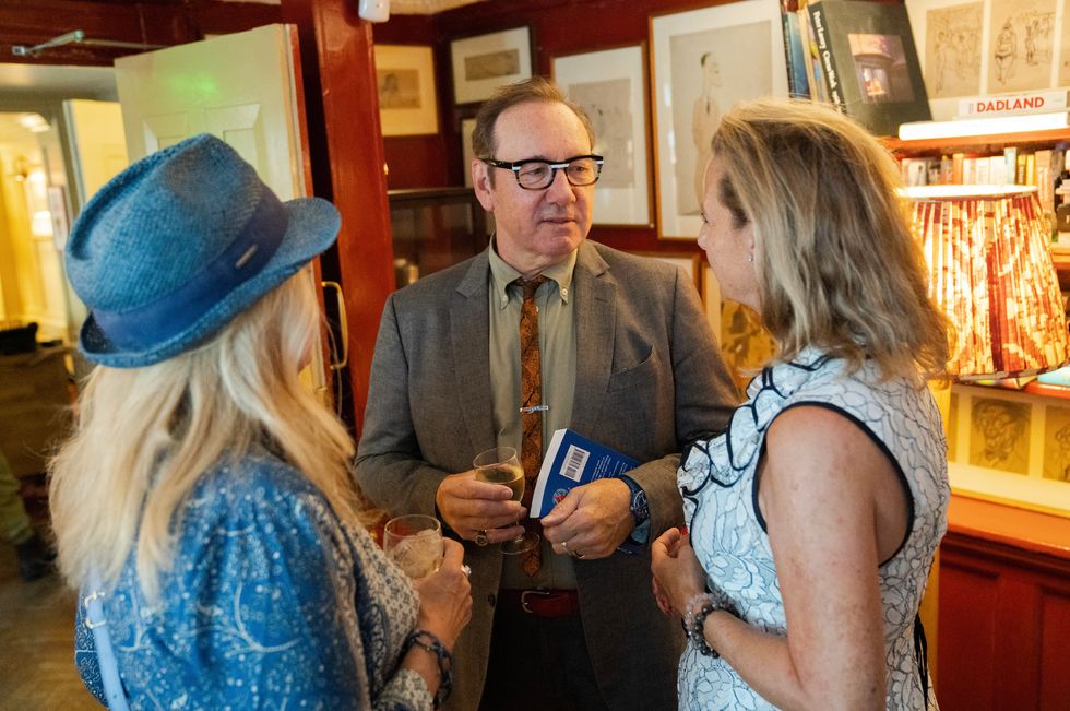 Kevin Spacey holding a glass of wine at the book launch