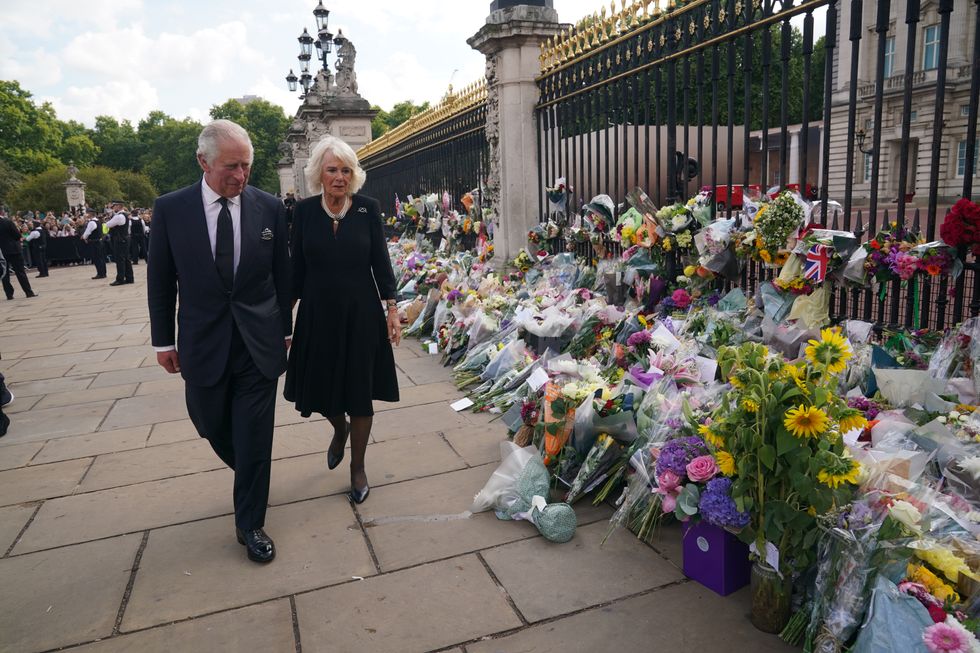 King Charles III and Camilla, Queen Consort look at the tributes left for Queen Elizabeth outside Buckingham Palace
