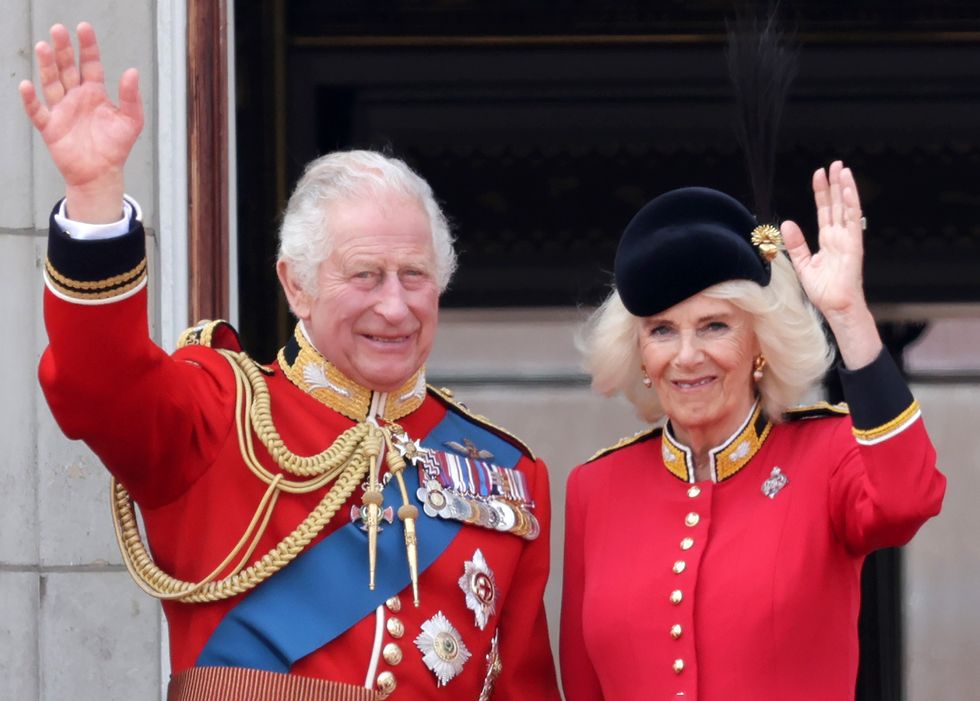 King Charles III and Queen Camilla wave as they watch the fly-past on the Buckingham Palace balcony