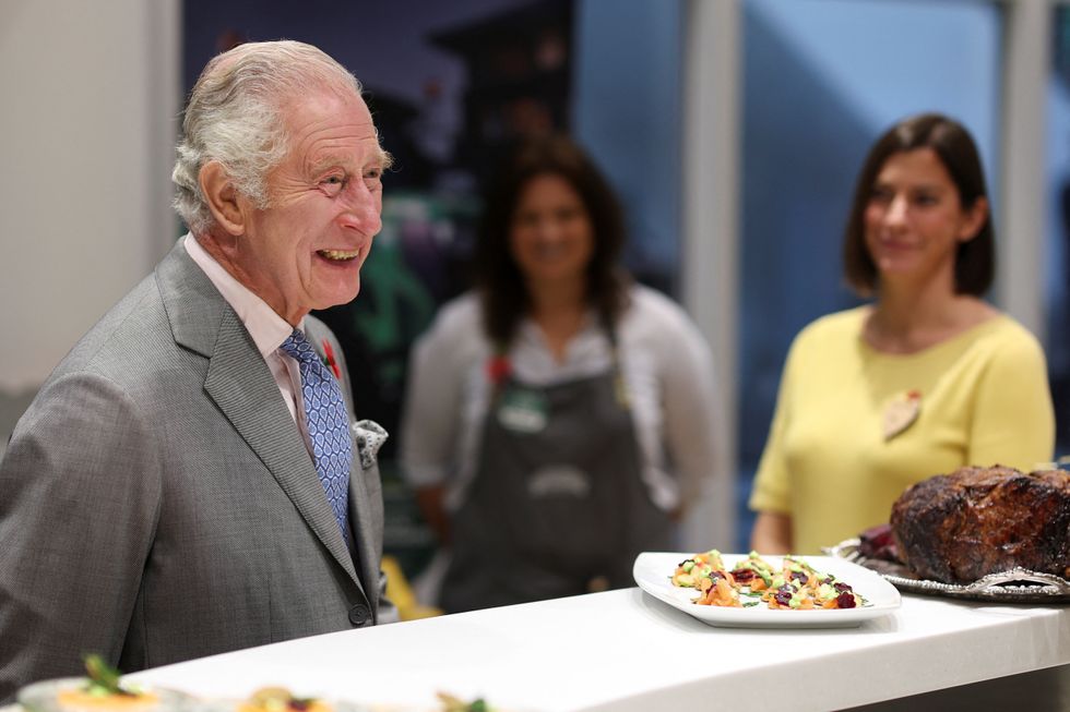 King Charles III smiles as he speaks to members of Morrisons staff.