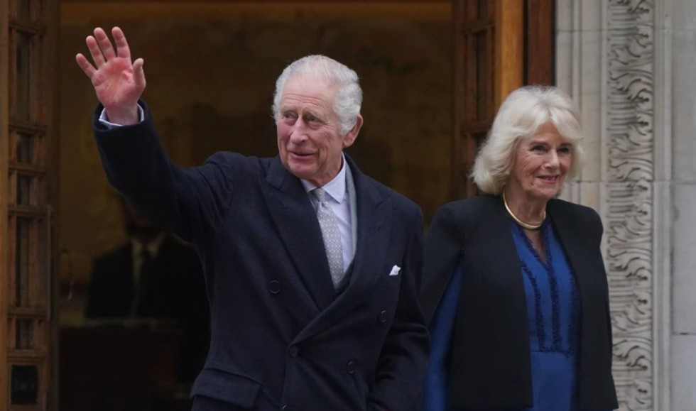 King Charles waving next to Queen Camilla
