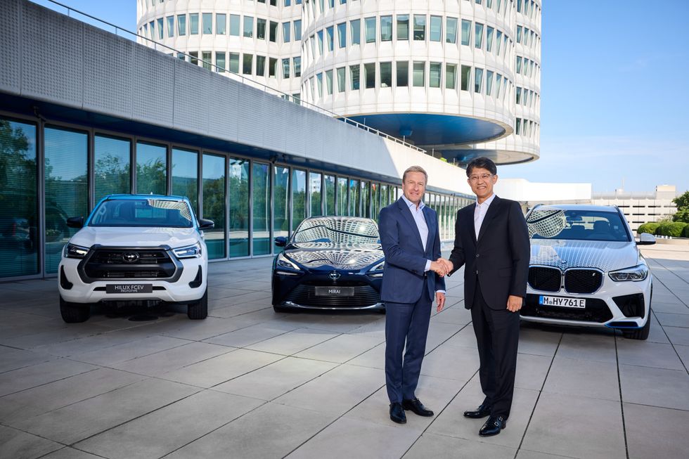 Koji Sato, President of Toyota, and BMW Chairman Oliver Zipse in front of three hydrogen vehicles