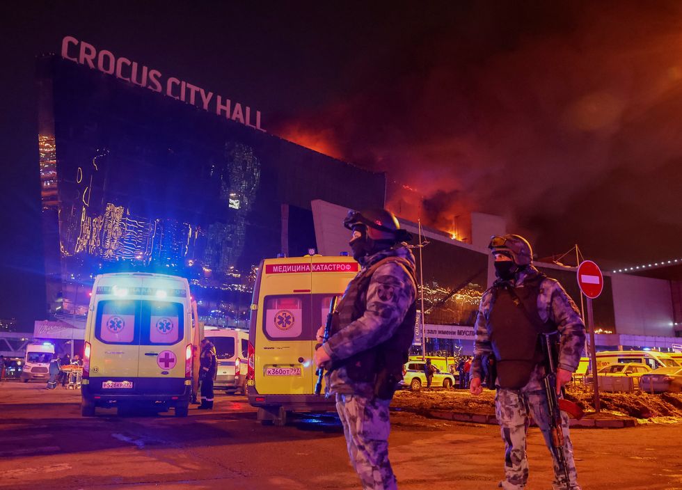 Law enforcement officers stand guard near the burning Crocus City Hall concert venue following a shooting incident