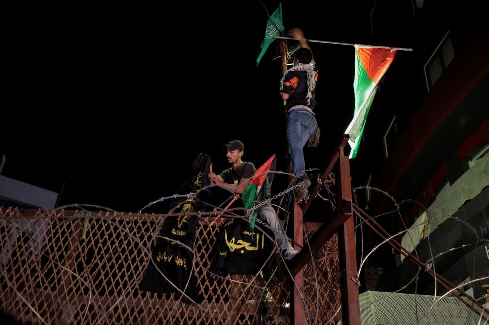 Lebanese protesters hang the Palestinian flag and signs on fence of the US embassy fence after hundreds of Palestinians were killed in a blast at Al-Ahli hospital in Gaza