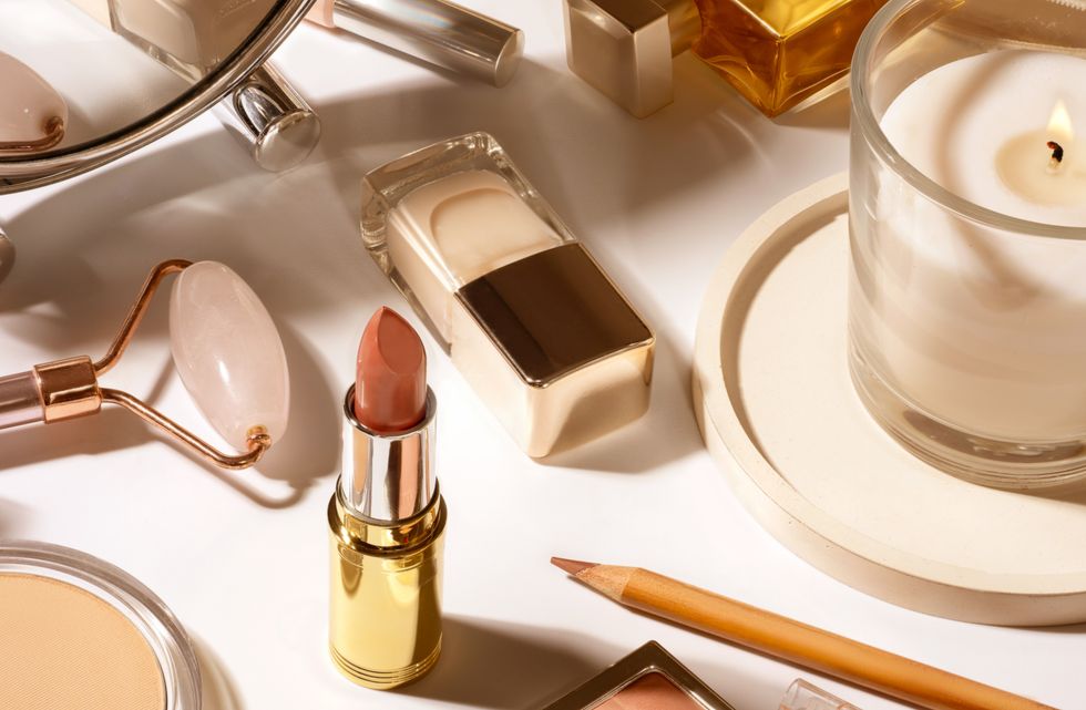 Lipstick and foundation laid out on a blank surface