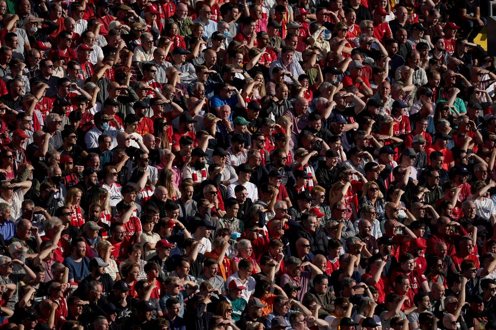 Liverpool fans shield their eyes from the sun while watching the game during the Premier League match at Anfield, Liverpool.