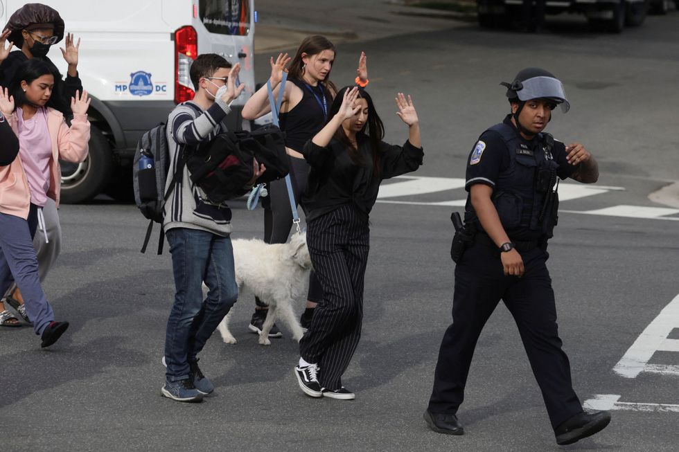 Local residents are escorted by Washington, D.C. Metropolitan Police officers to safety while being asked to keep their hands in the air at the scene of a reported shooting and active shooter near Edmund Burke Middle School in the Cleveland Park neighborhood of Northwest Washington, U.S., April 22, 2022. REUTERS/Evelyn Hockstein