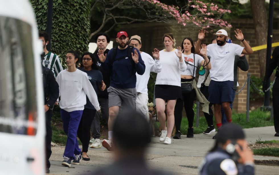 Local residents hold their hands in the air as police evacuate people to safety at the scene of a reported shooting and active shooter near Edmund Burke Middle School in the Cleveland Park neighborhood of Northwest Washington, U.S., April 22, 2022. REUTERS/Evelyn Hockstein