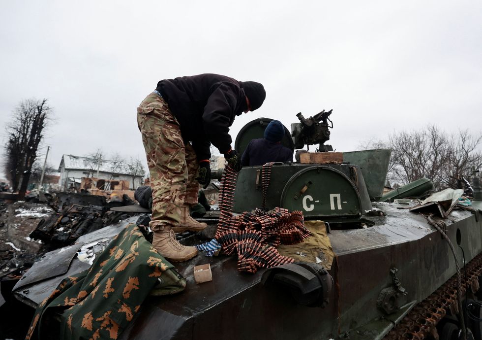 Local residents pick up ammunition from a destroyed armoured vehicle, as Russia's invasion of Ukraine continues, in the town of Bucha in the Kyiv region, Ukraine March 1, 2022. Picture taken March 1, 2022. REUTERS/Serhii Nuzhnenko