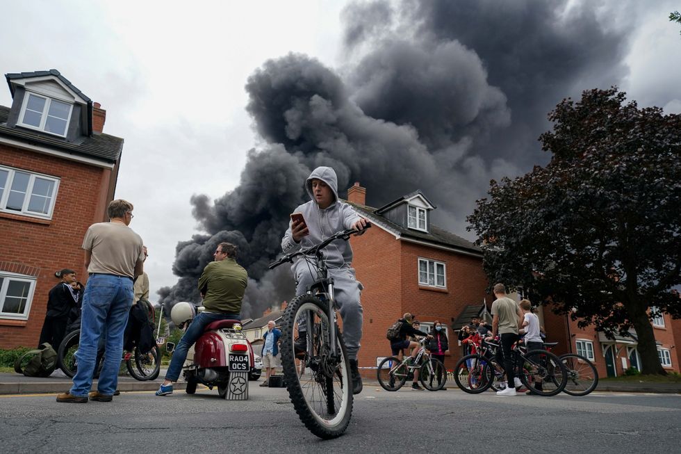 Local residents watch a large fire at an industrial premises in Juno Drive, Leamington Spa, Warwickshire. Picture date: Thursday August 27, 2021.