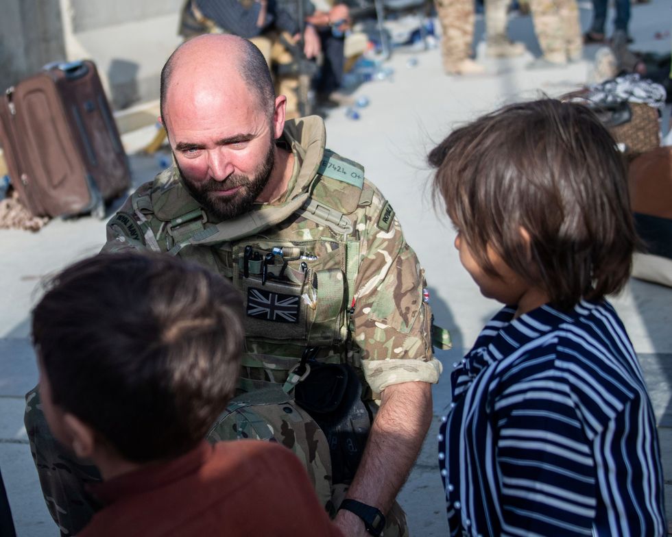 Lt Cdr Alex Pelham Burns a member of the UK Armed Forces speaks to children as he continues to take part in the evacuation of entitled personnel from Kabul airport.