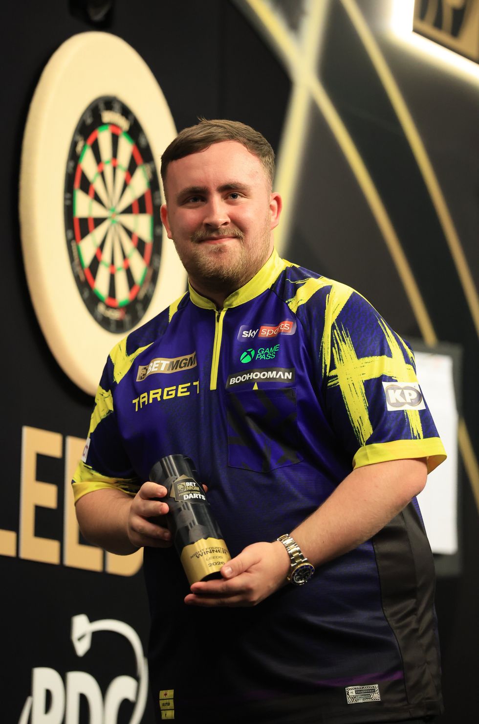 Luke Littler poses with his Premier League trophy after his victory in Leeds