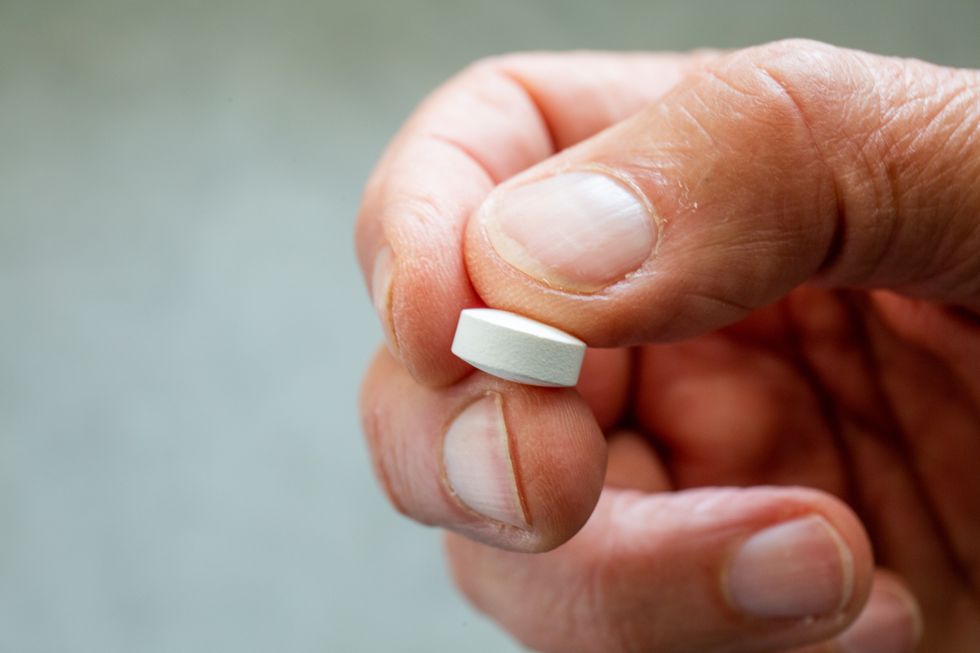 Male hand holding white pill