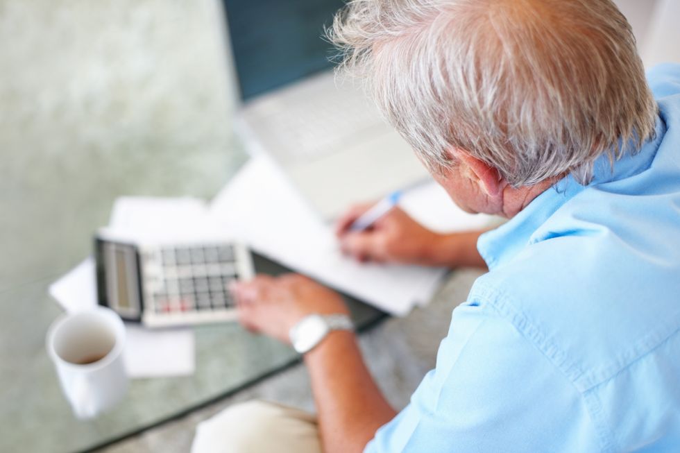 Male pensioner looks at calculator and paper