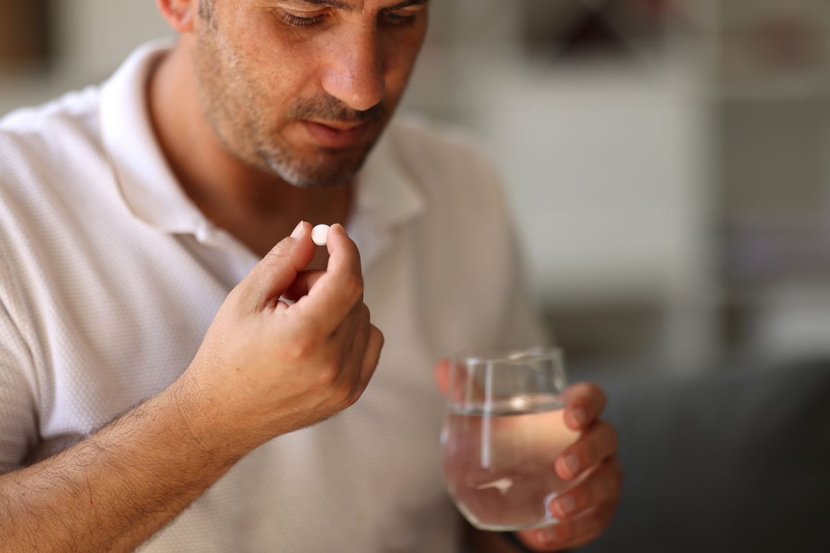 Man about to take a pill with water 
