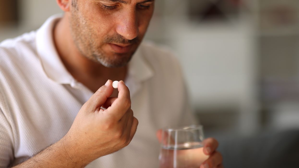 Man about to take a pill with water