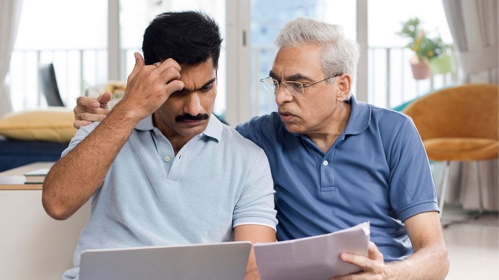 Man at son at laptop checking bills
