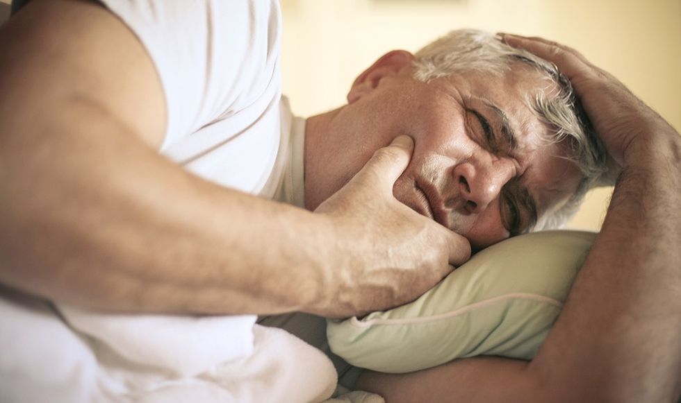 Man gripping his head in bed