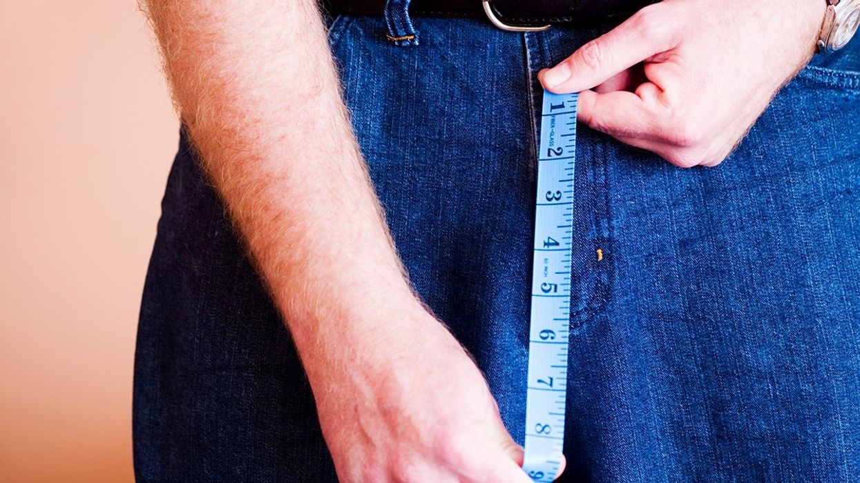 Man holding a measuring tape in front of his crouch
