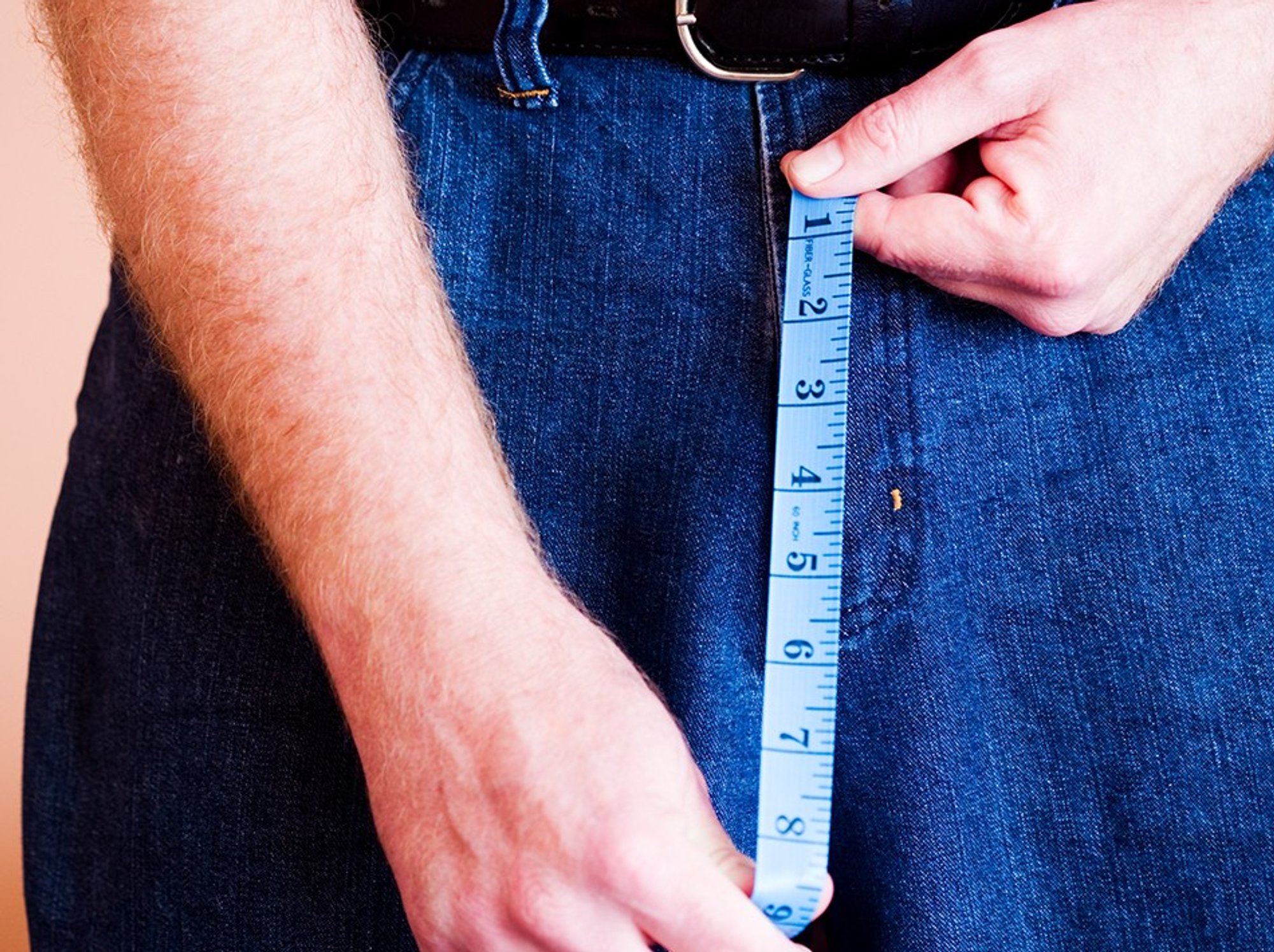 Man holding a measuring tape in front of his crouch