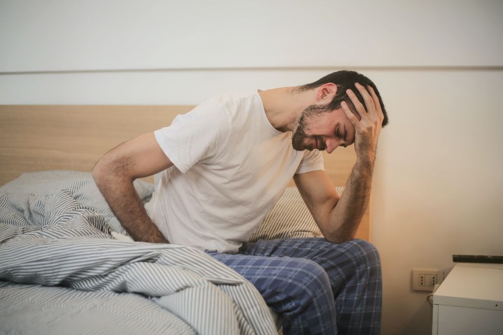 Man holding back and head in bed