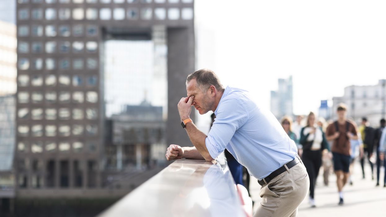 Man holding his eyes on a busy street