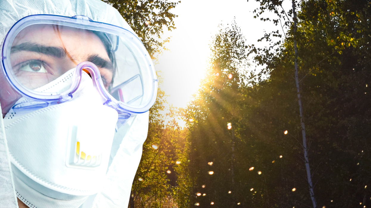 Man in a hazmat suit looking up at flies