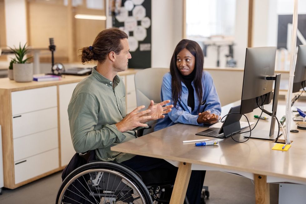 Man in wheelchair working alongside woman
