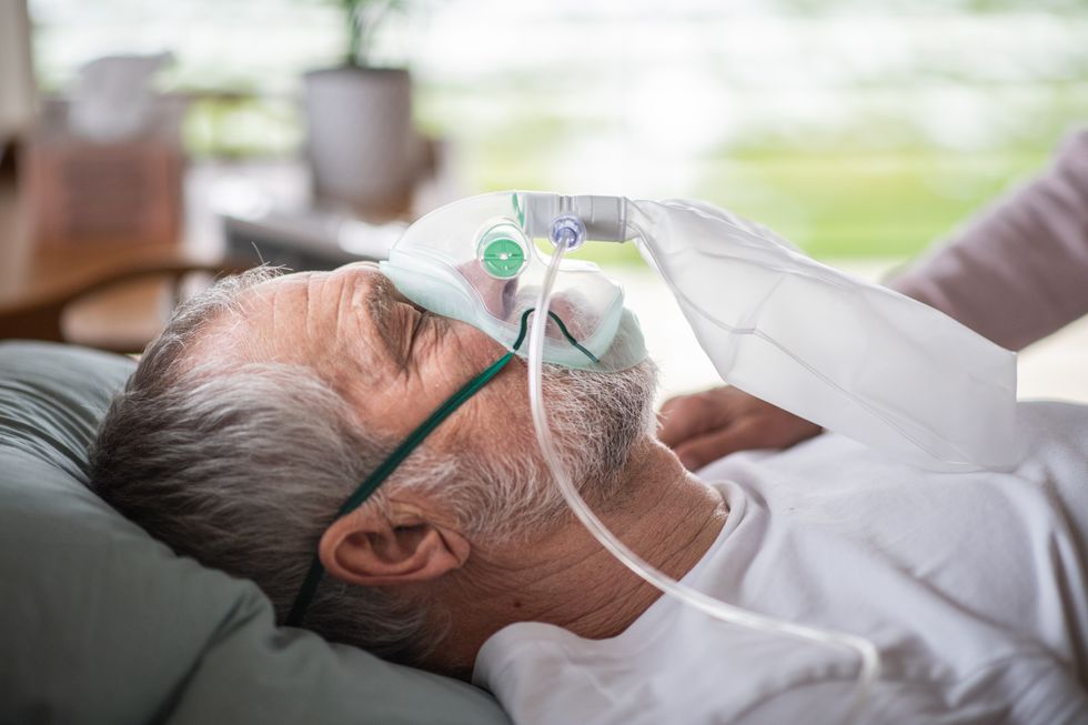 Man laying in bed with oxygen mask