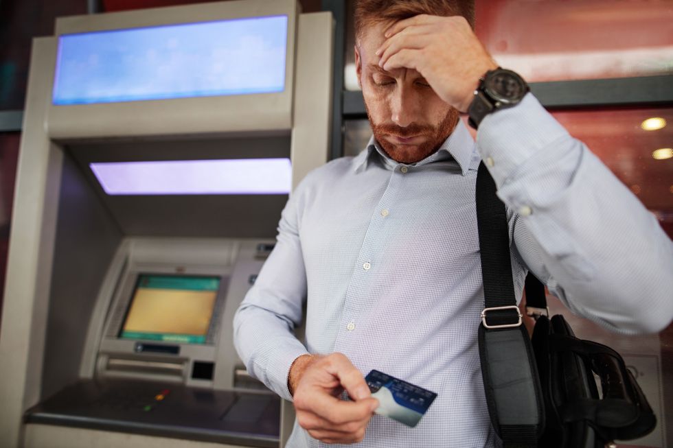 Man looking stressed next to a cash machine