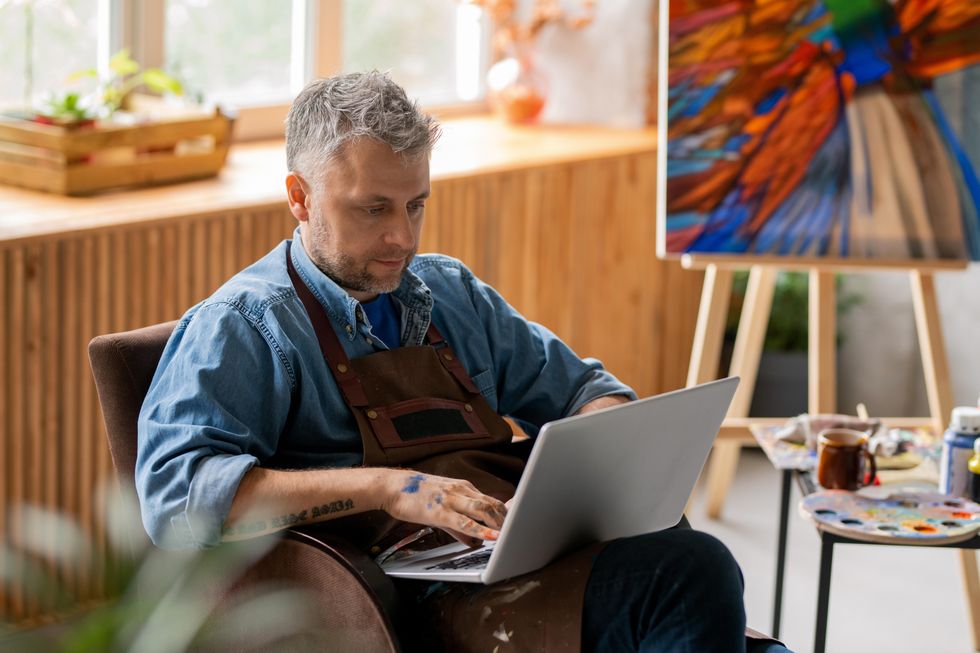 Man looks at laptop in his art studio