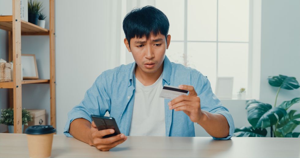 Man looks worried at credit card and phone