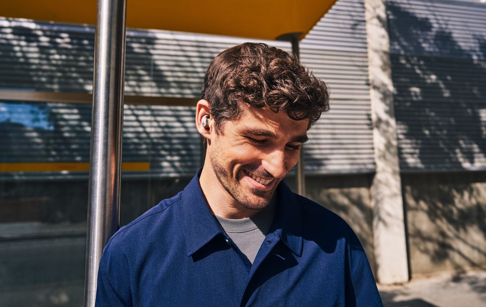 Man pictured smiling with the Gravel Grey Powerbeats Fit in his ears