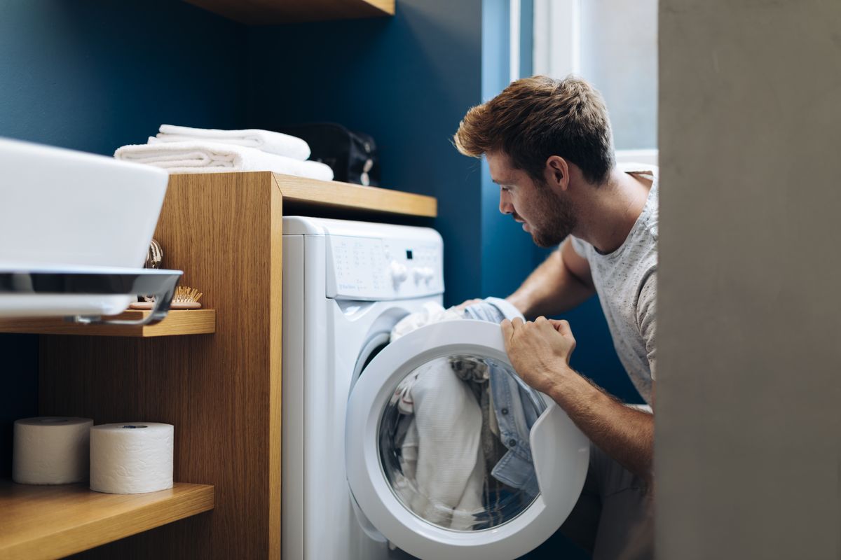 Man puts laundry into washing machine