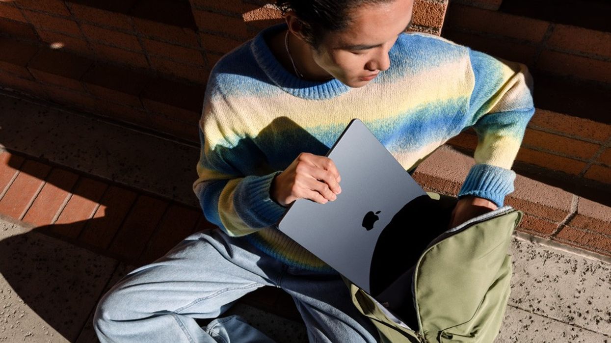 man sits on the floor and puts the m3 macbook air into a backpack