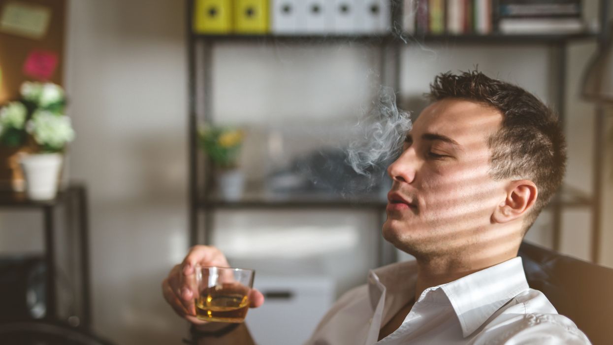 Man sitting back in a chair smoking and drinking