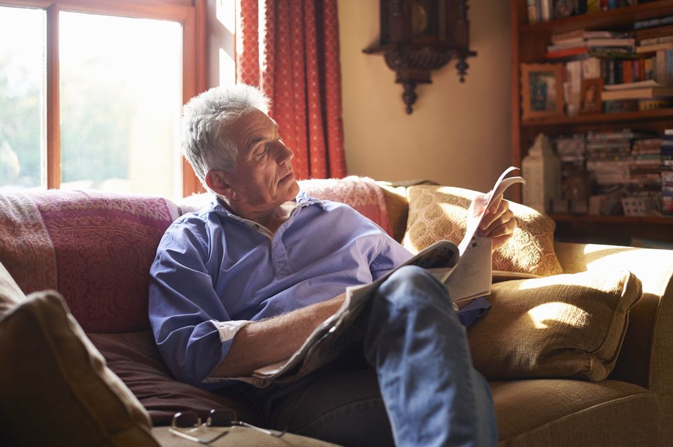 Man sitting on his sofa reading a newspaper