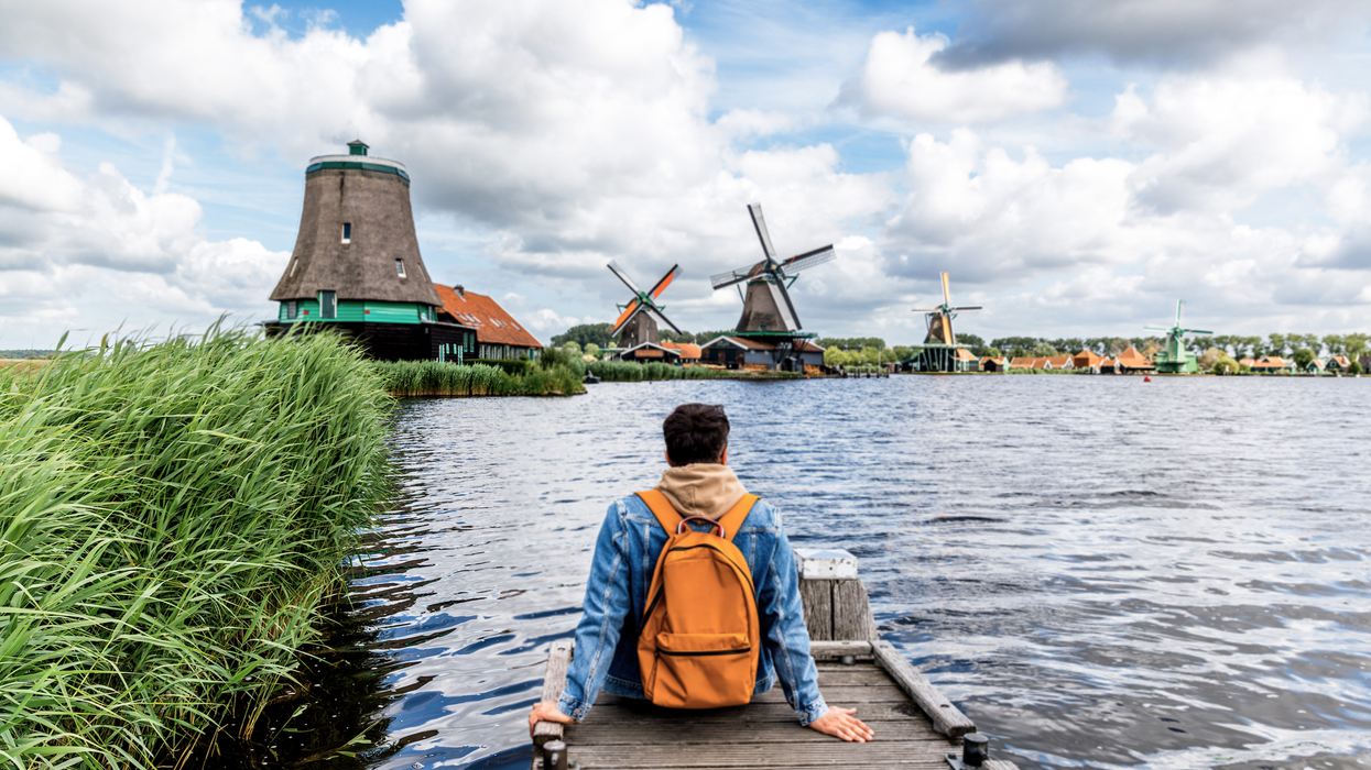 Man sitting on the pier and looking at windmills in Zaanse Schans, Zaandam, Netherland
