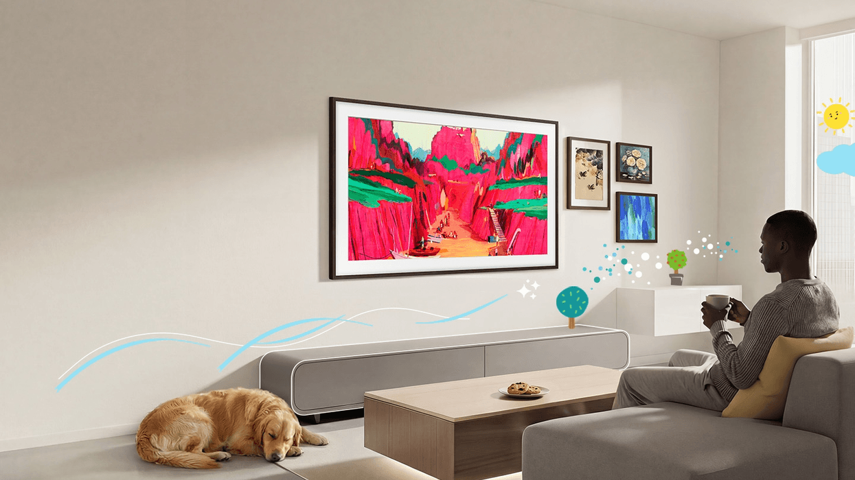 Man sitting with a cup of tea on the sofa watching artwork on the frame tv from samsung
